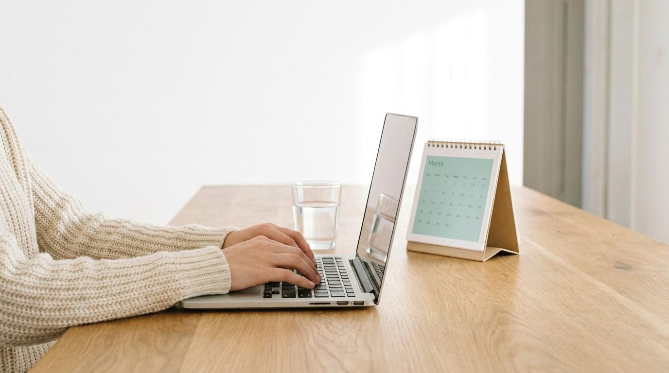 Hands typing on a laptop next to a calendar, showing side hustles from home 2026 planning.